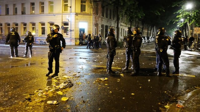 Polizisten sichern eine Straße im Osten der Stadt, im Hintergrund sind die Reste einer Barrikade zu sehen: Nach einer Hausräumung ist es in Leipzig zu Ausschreitungen gekommen.