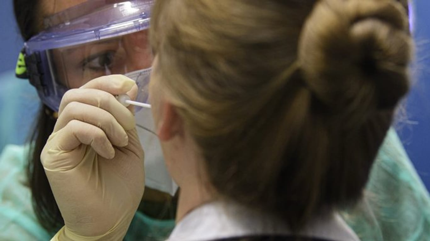 Eine Ärztin nimmt in der Corona-Teststation für Urlaubsrückkehrer am Flughafen Dresden International bei einer Frau einen Abstrich für eine Coronavirus-Test.