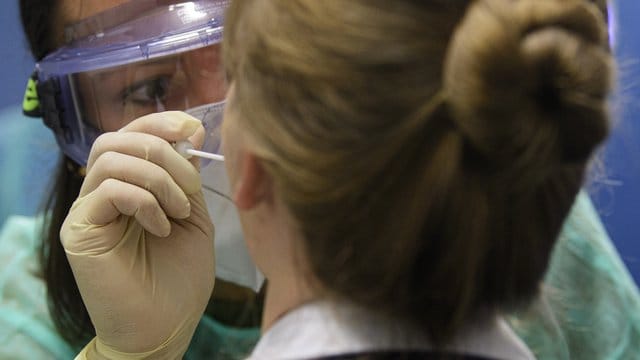 Eine Ärztin nimmt in der Corona-Teststation für Urlaubsrückkehrer am Flughafen Dresden International bei einer Frau einen Abstrich für eine Coronavirus-Test.