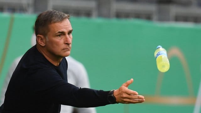 U21-Trainer Stefan Kuntz wirft einem seiner Spieler eine Getränkeflasche zu.