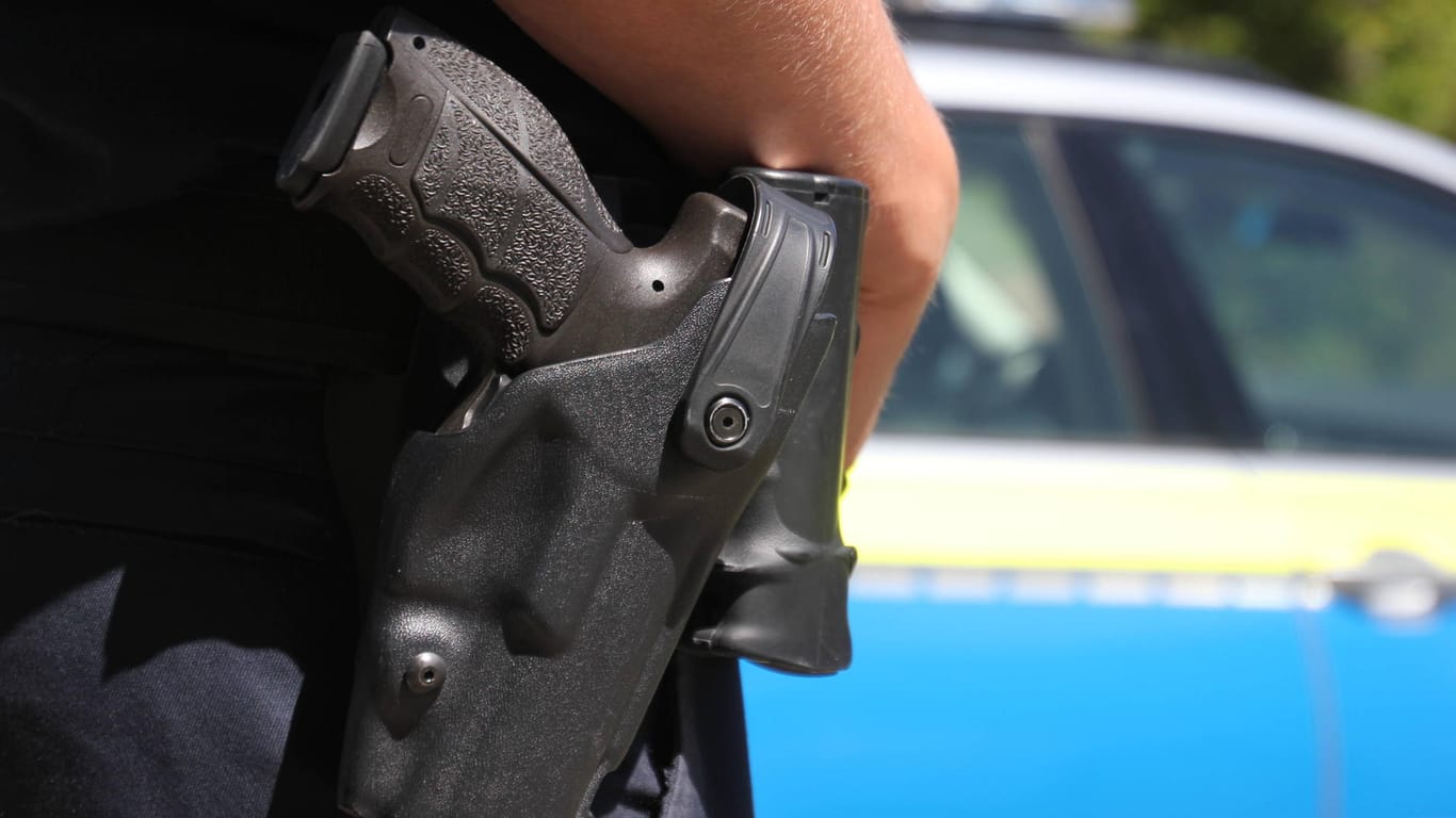 Ein Polizist legt seine Hand auf eine Waffe ab (Symbolbild): Ein 29-Jähriger soll in Essen ausgeraubt und mit einer Waffe bedroht worden sein.
