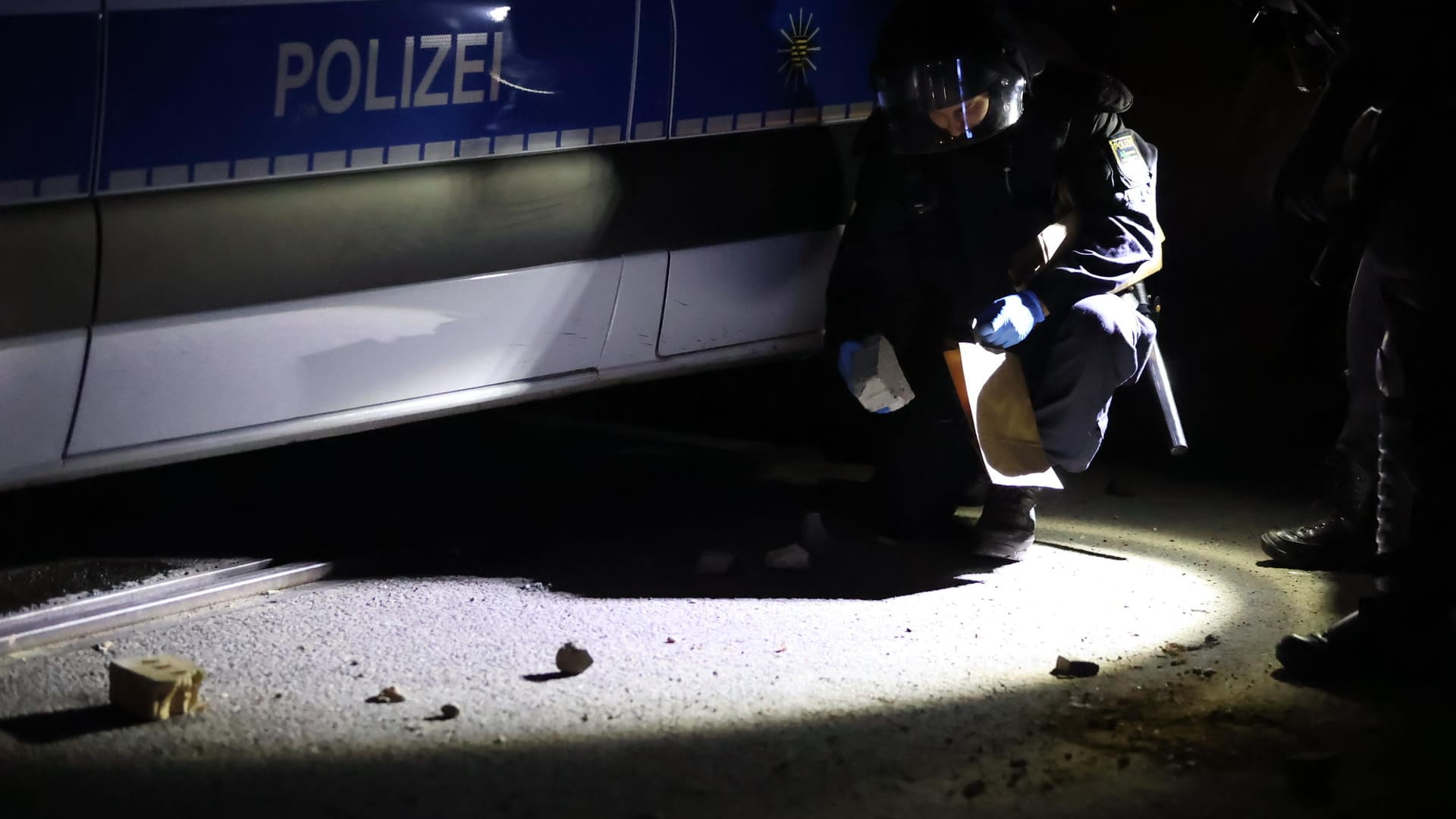 Ein Beamter sichert Steine als Beweismittel: Eine von der Polizei beendete Hausbesetzung ist Ausgangspunkt der Auseinandersetzungen.