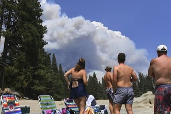 Eine Familie beobachtet vom Ufer des Shaver Lake aus den aufsteigenden Rauch eines Waldbrandes.