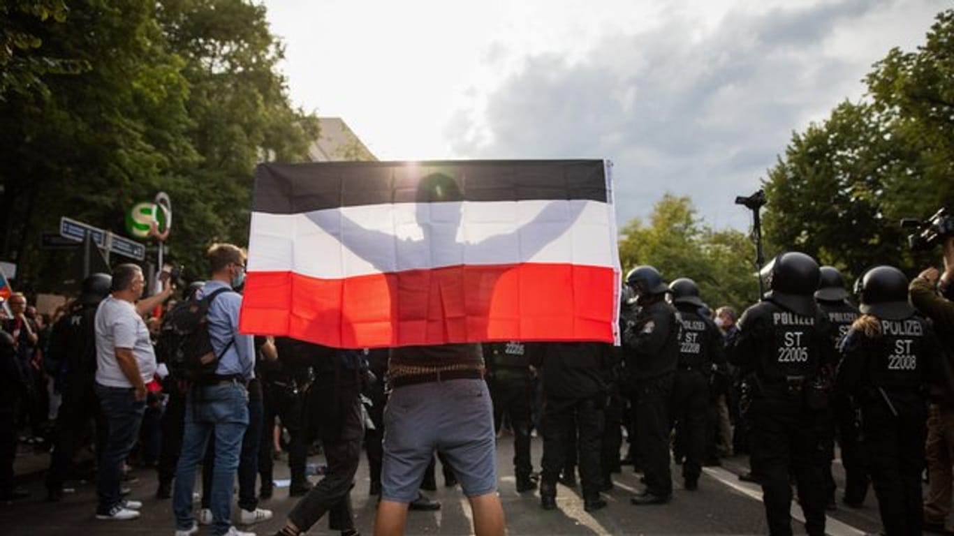 Ein Mann hält eine Reichsflagge bei einem Protest gegen die Corona-Maßnahmen.