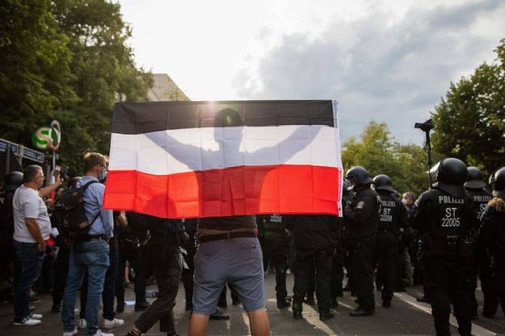 Ein Mann hält eine Reichsflagge bei einem Protest gegen die Corona-Maßnahmen.