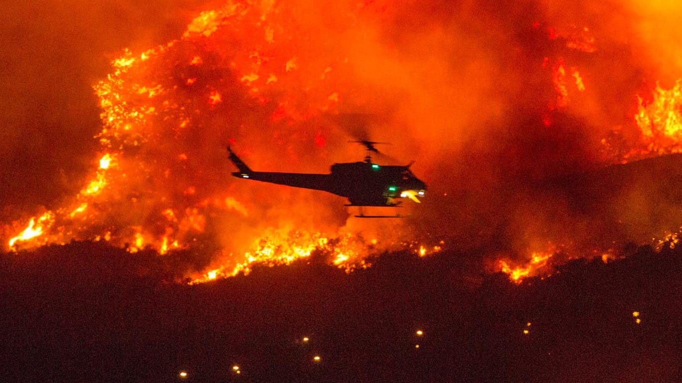 "Historische Waldbrände": Ein Löschhubschrauber fliegt im San Bernardino County über ein Flammenmeer.