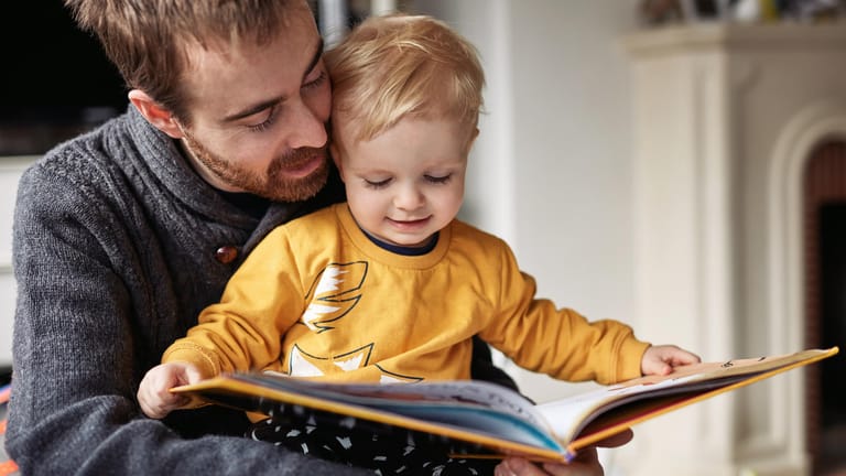 Ein Vater liest seinem Kind vor (Symbolbild): Der Kinderbonus von 300 Euro kommt nicht allen Eltern gleich stark zugute.