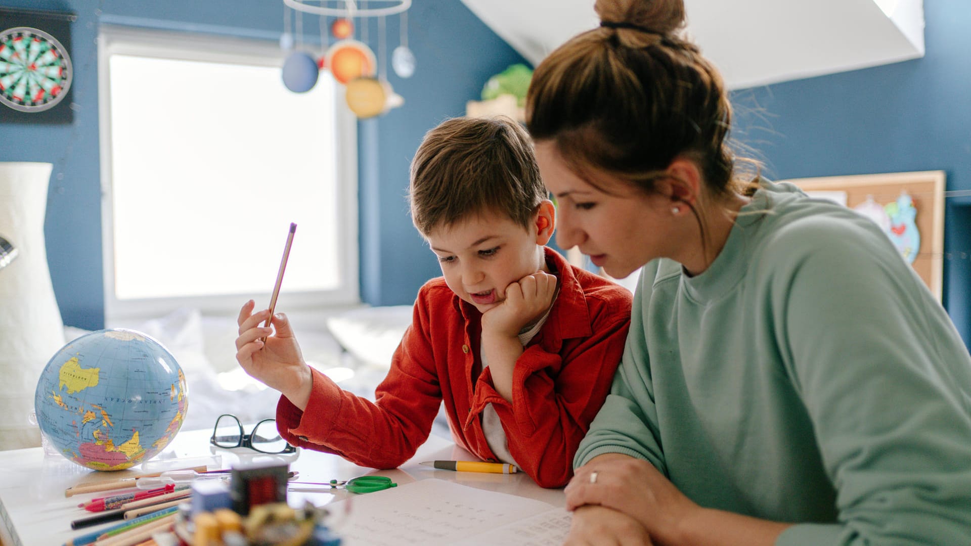 Mutter betreut Sohn bei den Schulaufgaben