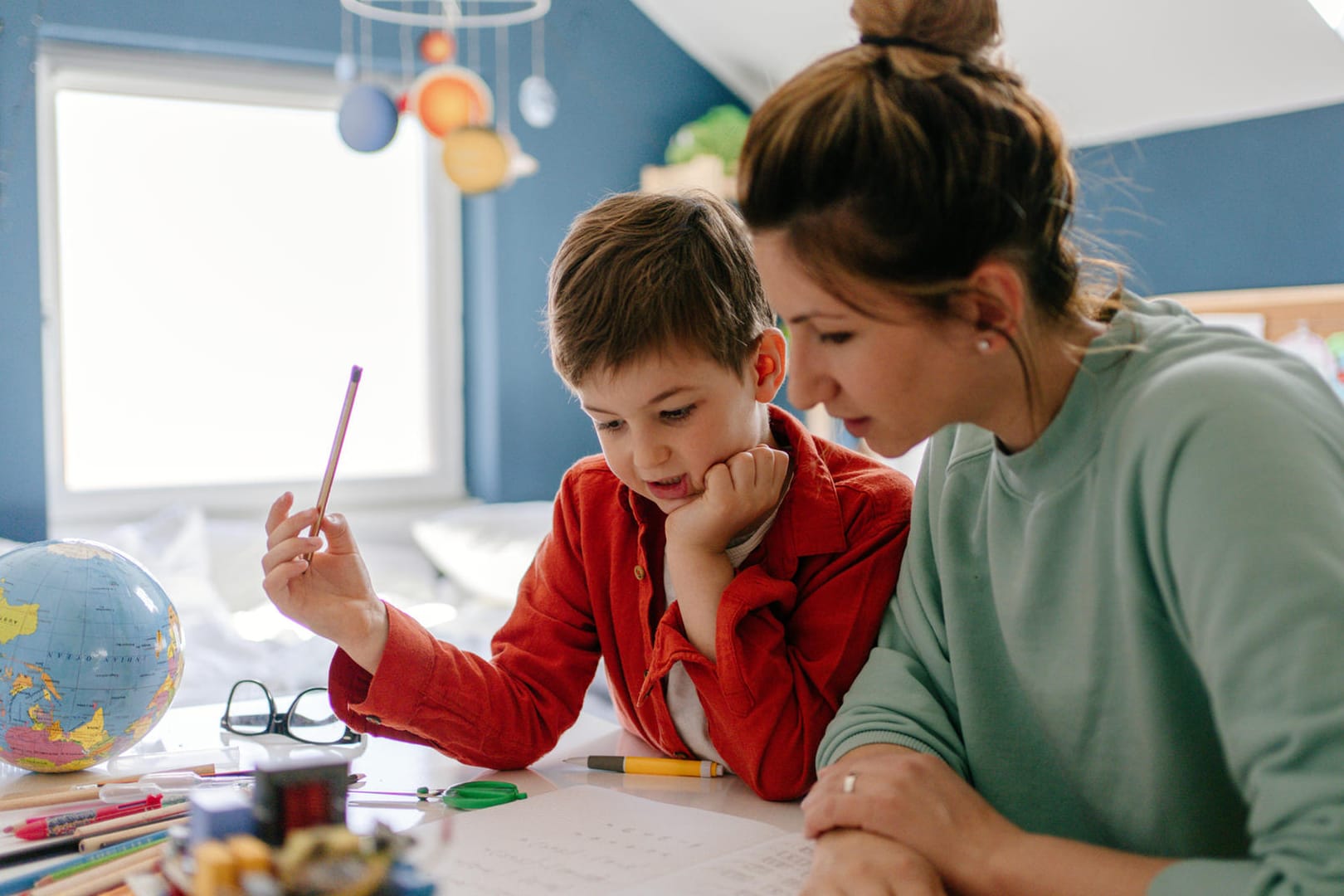 Mutter betreut Sohn bei den Schulaufgaben