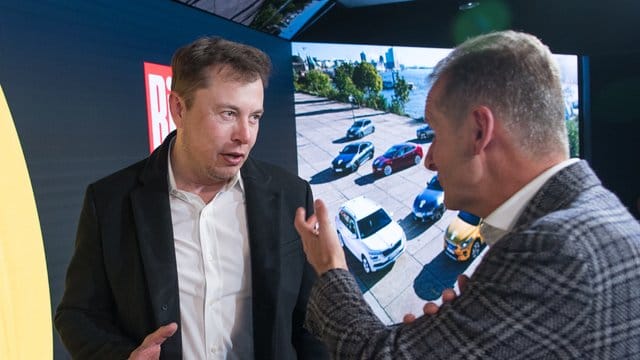Elon Musk und Herbert Diess unterhalten sich bei einem Treffen