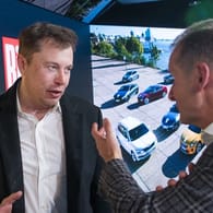 Elon Musk und Herbert Diess unterhalten sich bei einem Treffen