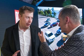Elon Musk und Herbert Diess unterhalten sich bei einem Treffen