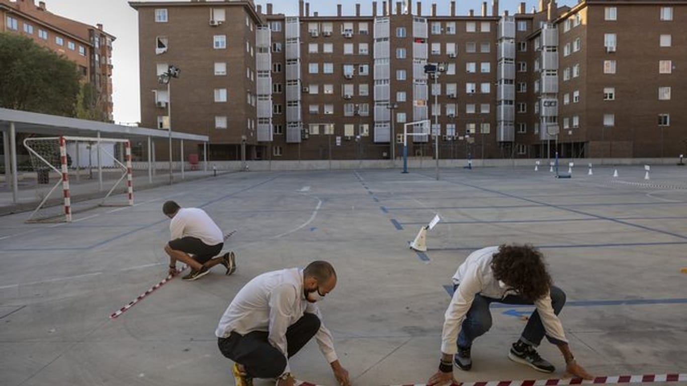 Lehrer machen mit Klebeband Markierungen auf einem Schulhof in Madrid, um den Sicherheitsabstand zwischen den Schülern zu gewährleisten.