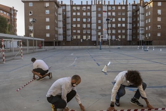 Lehrer machen mit Klebeband Markierungen auf einem Schulhof in Madrid, um den Sicherheitsabstand zwischen den Schülern zu gewährleisten.