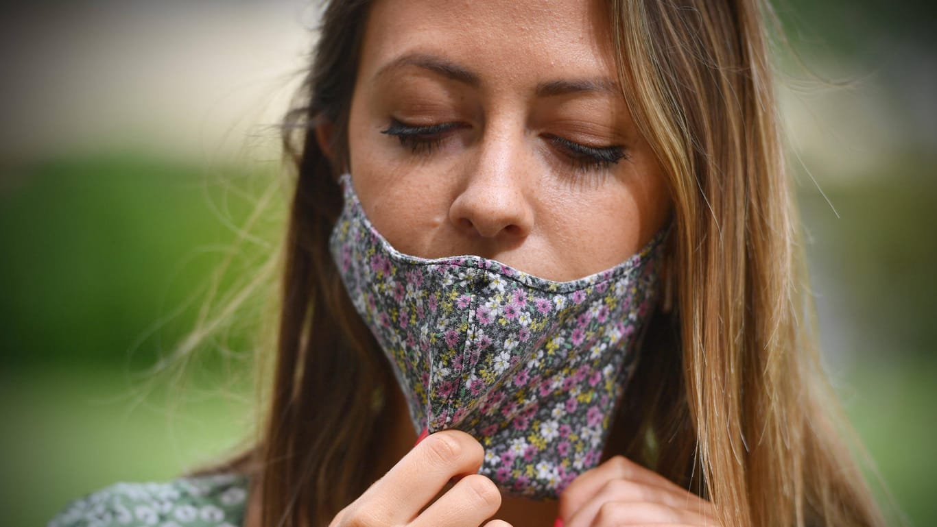Eine Frau mit Mundschutz und unbedeckter Nase (Symbolbild): Auch falsches Tragen der Maske wird bestraft.
