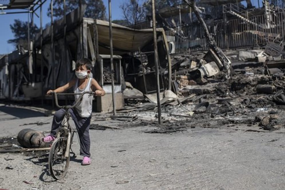Ein Junge steht vor verbrannten Trümmern in Moria.