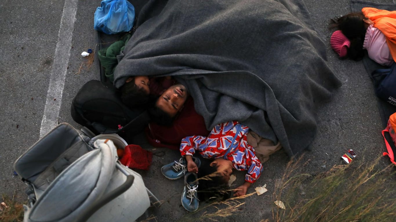 Alles verloren: Eine Familie schläft in eine Decke gehüllt auf einem Parkplatz.