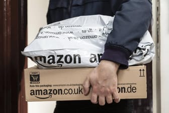 Paketbote übergibt zwei Amazon-Pakete (Symbolbild): Das Kartellamt soll eine marktbeherrschende Stellung großer Online-Konzerne künftig stärker kontrollieren.