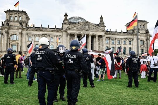 Teilnehmer einer Demonstration gegen die Corona-Maßnahmen stehen mit Reichsflaggen vor dem Reichstag.