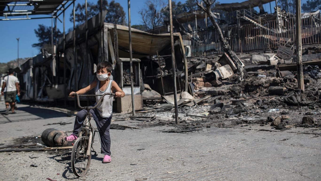Lesbos: Ein Junge fährt mit einem beschädigten Fahrrad neben den verbrannten Trümmern im Flüchtlingslager Moria auf der nordöstlichen Ägäisinsel Lesbos.