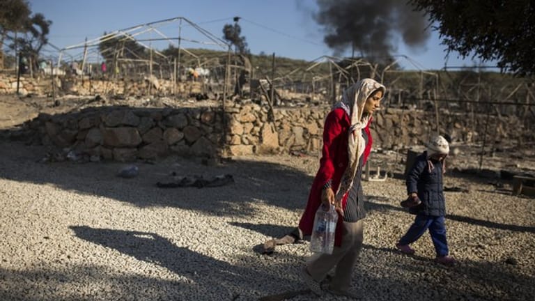 Eine Frau geht mit ihrem Kind durch das ausgebrannte Flüchtlingslager Moria.