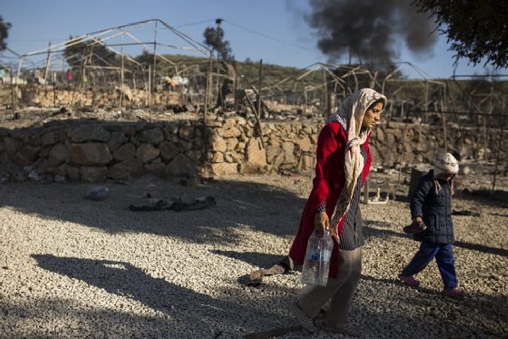 Eine Frau geht mit ihrem Kind durch das ausgebrannte Flüchtlingslager Moria.