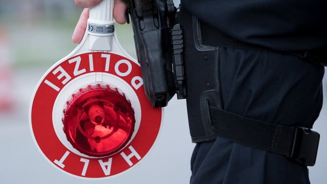 Ein Polizist hält eine Kelle in der Hand Ein Polizist hält eine Kelle in der Hand