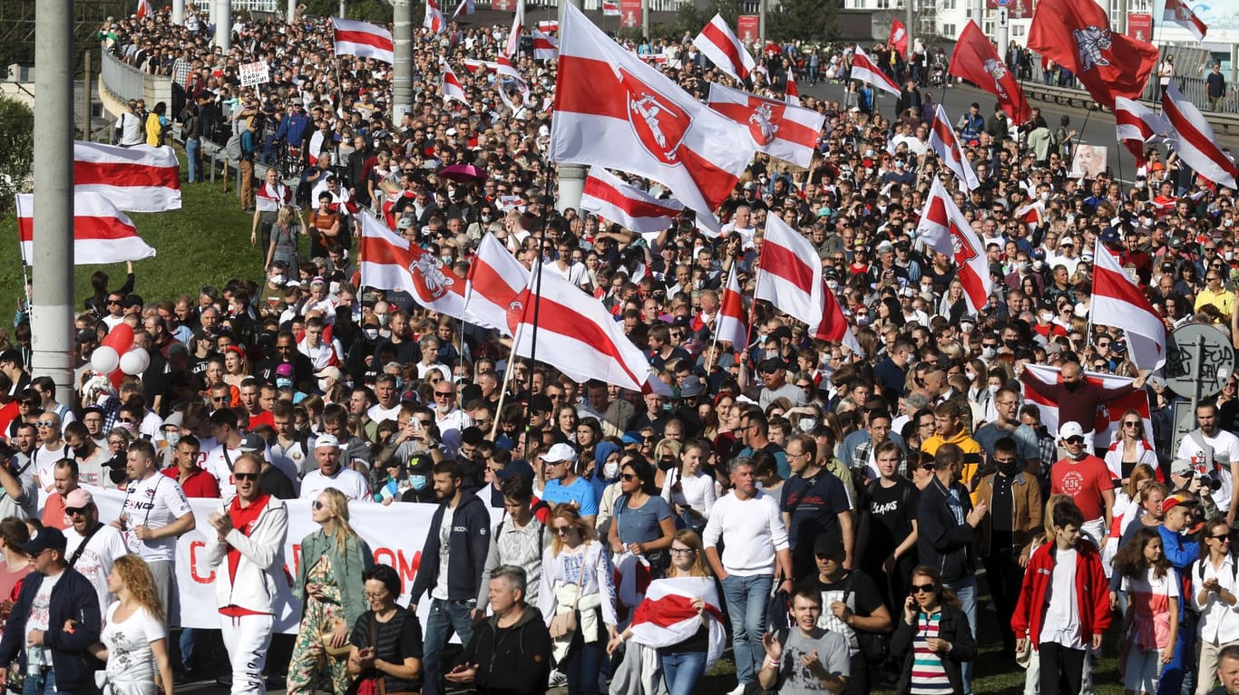 Belarus, Minsk: Demonstranten halten historische belarussische Flaggen und nehmen an einem Protest der Opposition teil.