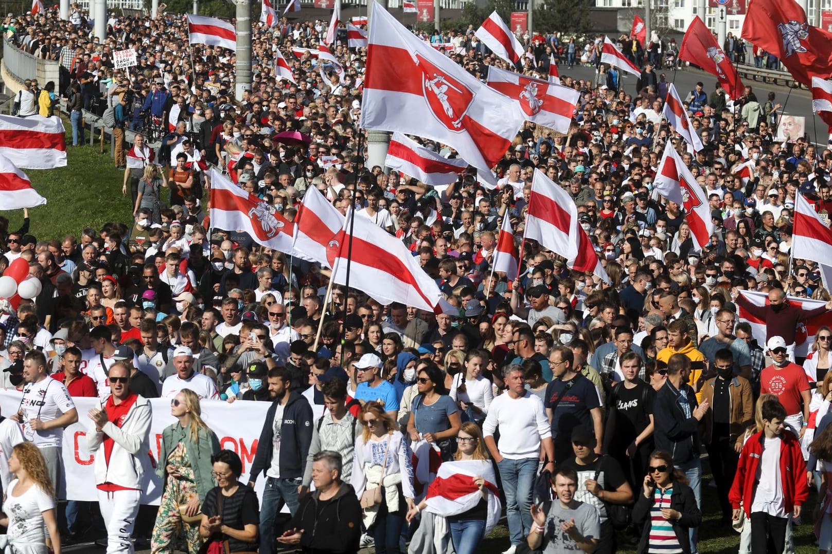 Belarus, Minsk: Demonstranten halten historische belarussische Flaggen und nehmen an einem Protest der Opposition teil.