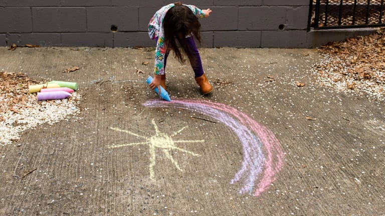 Ein Mädchen malt mit Kreide auf einem Fußweg (Symbolbild): Kinder sollen in Wolfsburg mit bunten Kreidebildern auf ihre Bedürfnisse aufmerksam machen.