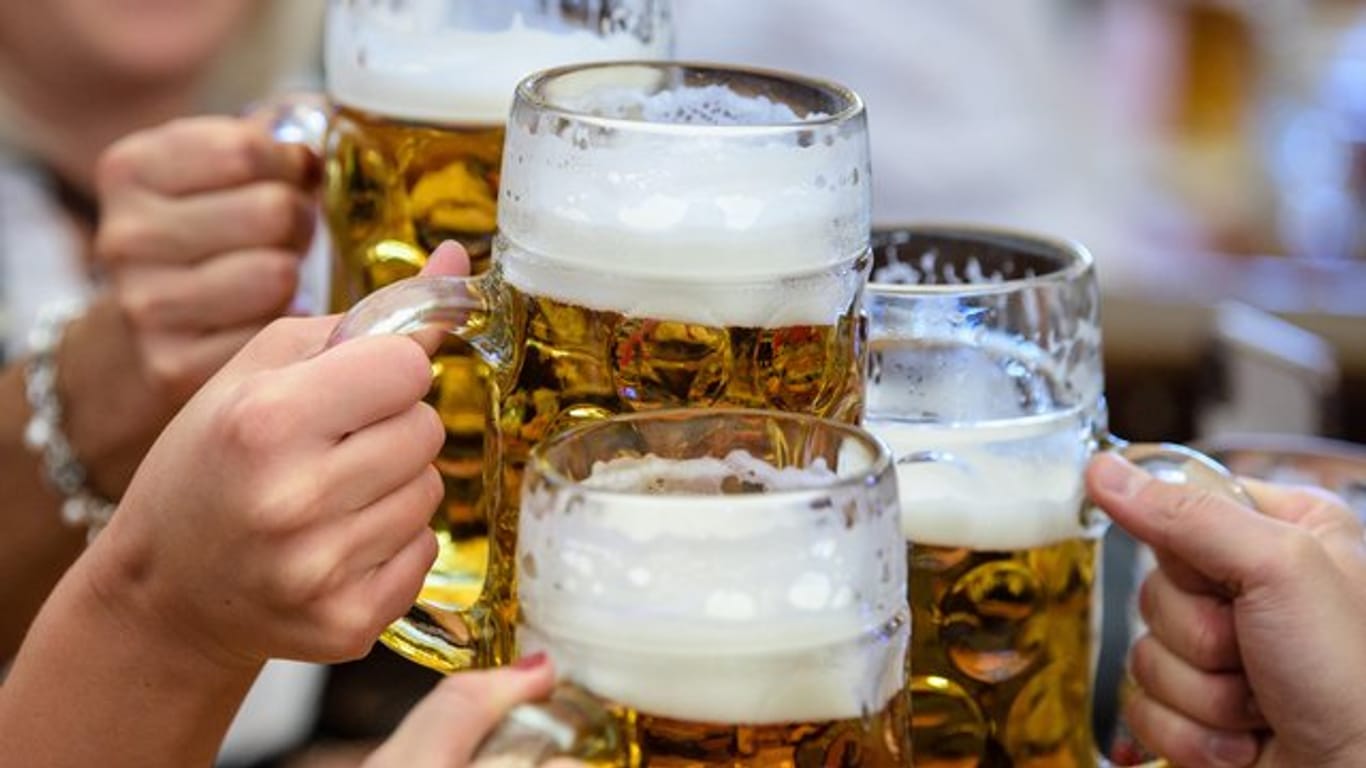 Menschen stoßen mit ihren Bierkrügen an (Symbolbild): Das Oktoberfest fällt dieses Jahr aus. Um private Feiern auf der Theresienwiese zu vermeiden, überlegt die Stadt München, dort ein Alkoholverbot zu verhängen.