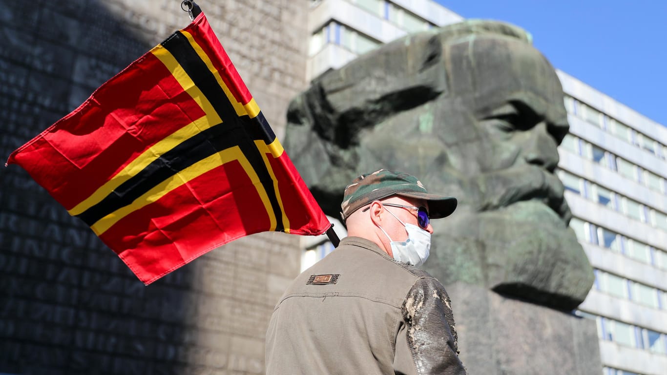 Sachsen, Chemnitz: Ein Teilnehmer der rechtsextremen Vereinigung Pro Chemnitz demonstriert mit der so genannten Wirmer-Flagge trotz Corona-Krise vor dem Karl-Marx-Monument.