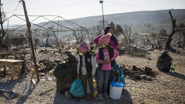 Eine Familie steht vor dem abgebrannten Flüchtlingslager Moria: Viele Menschen auf Lesbos sind nun obdachlos.