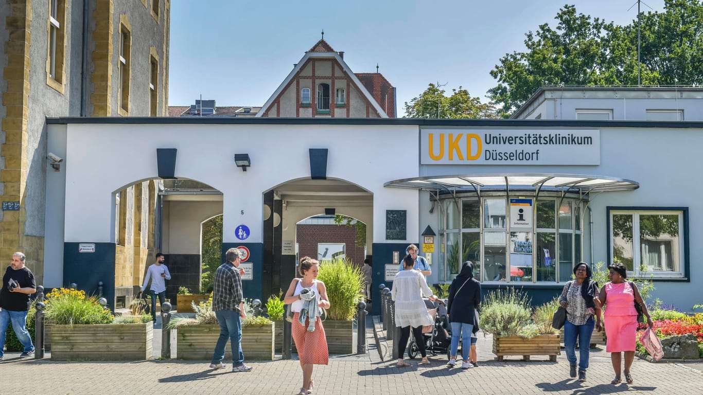 Menschen laufen vor dem Haupteingang des Düsseldorfer Universitätsklinikums: Für immer mehr Patienten wird der IT-Ausfall in der Klinik zum Problem.