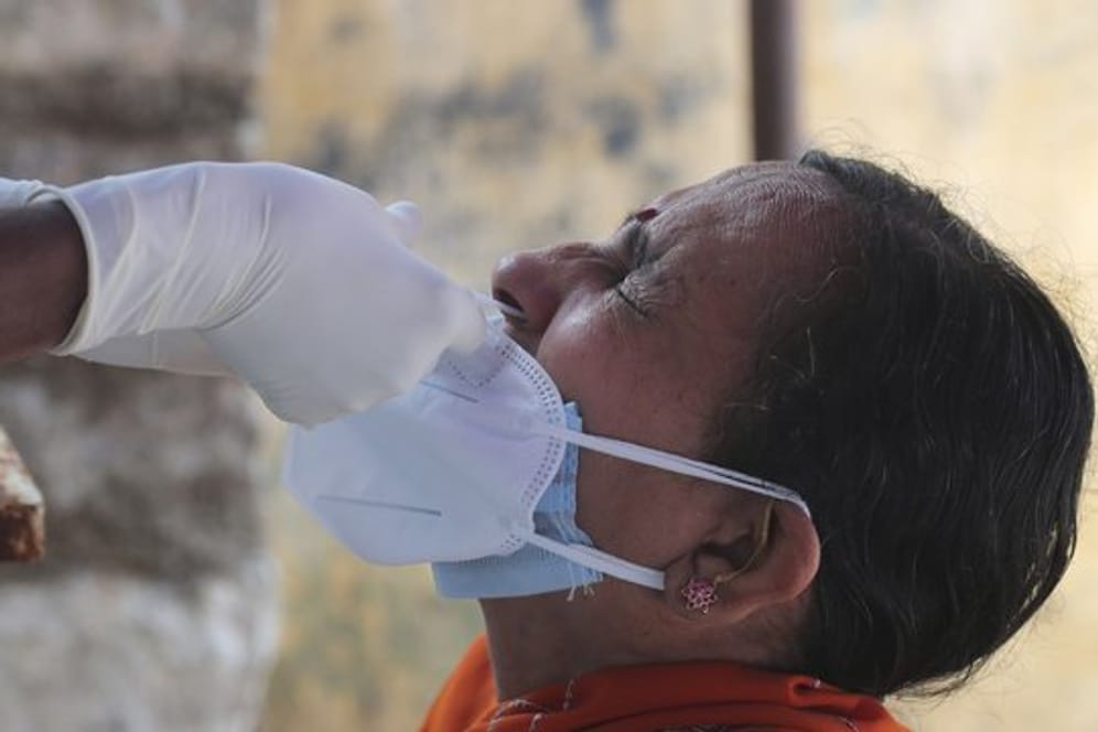 Ein medizinischer Mitarbeiterin der indischen Stadt Hyderabad entnimmt einer Frau einen Nasenabstrich für einen Corona-Test.