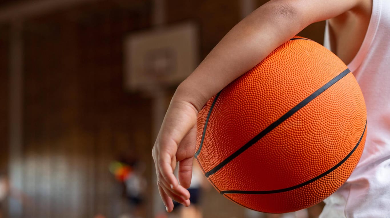 Ein Junge hat einen Basketball unter den Arm geklemmt (Symbolbild): In Hagen hat Phoenix Hagen wieder damit begonnen, Grundschülern den Sport näher zu bringen.