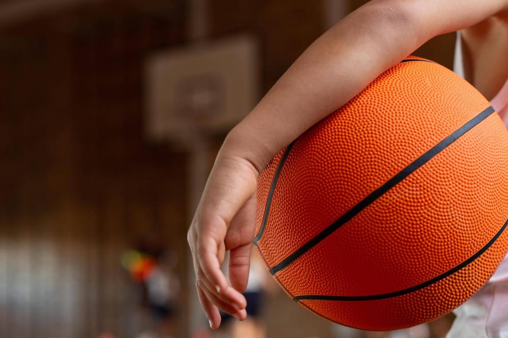 Ein Junge hat einen Basketball unter den Arm geklemmt (Symbolbild): In Hagen hat Phoenix Hagen wieder damit begonnen, Grundschülern den Sport näher zu bringen.