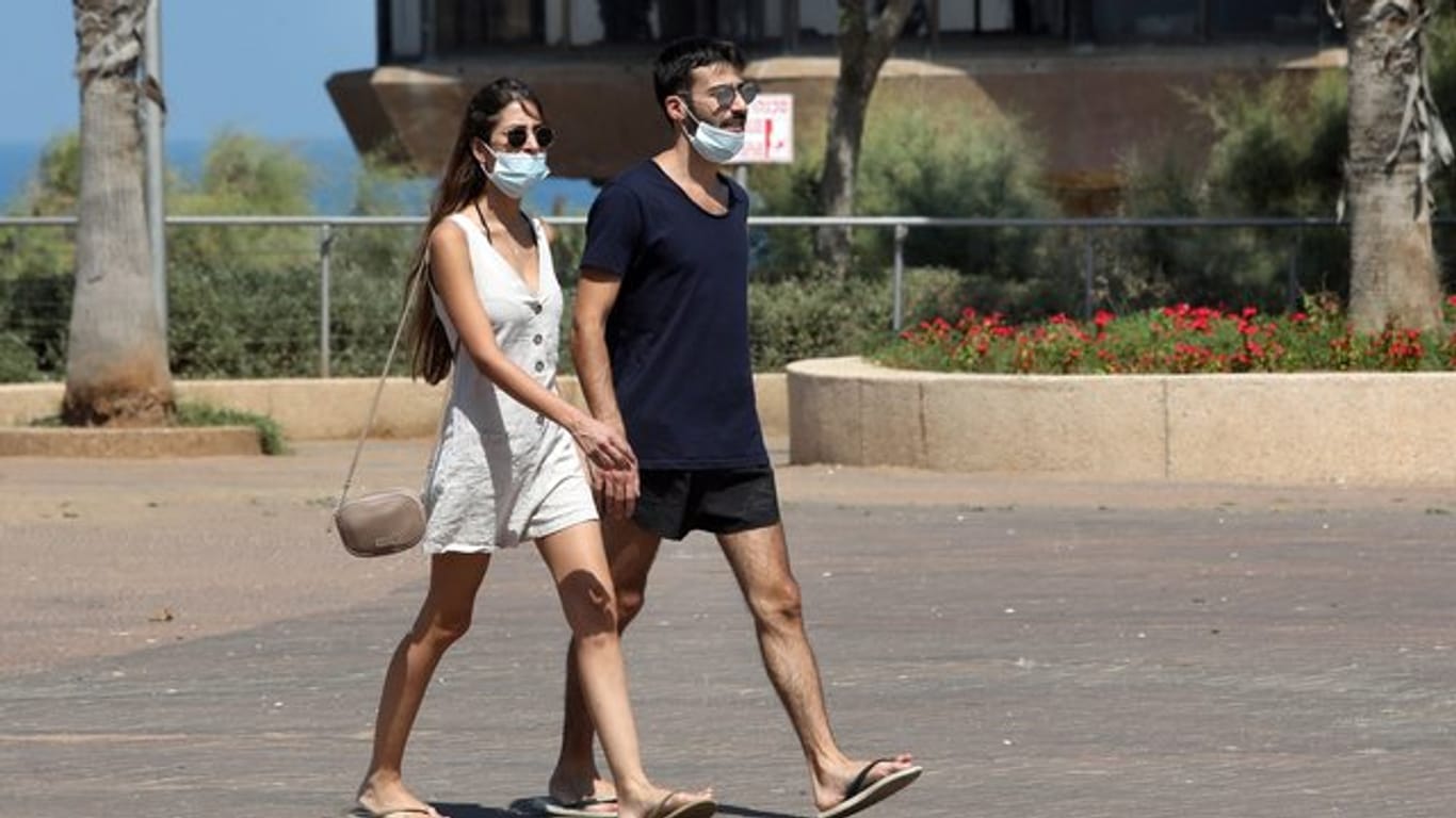 Passanten tragen Mundschutze, während sie auf einer Straße in Netanja gehen.