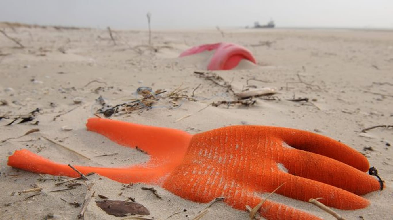 Angespülter Unrat in Form eines Arbeitshandschuhs und eines Kunststoffkanisters am Strand der Vogelschutzinsel Memmert, Niedersachsen.