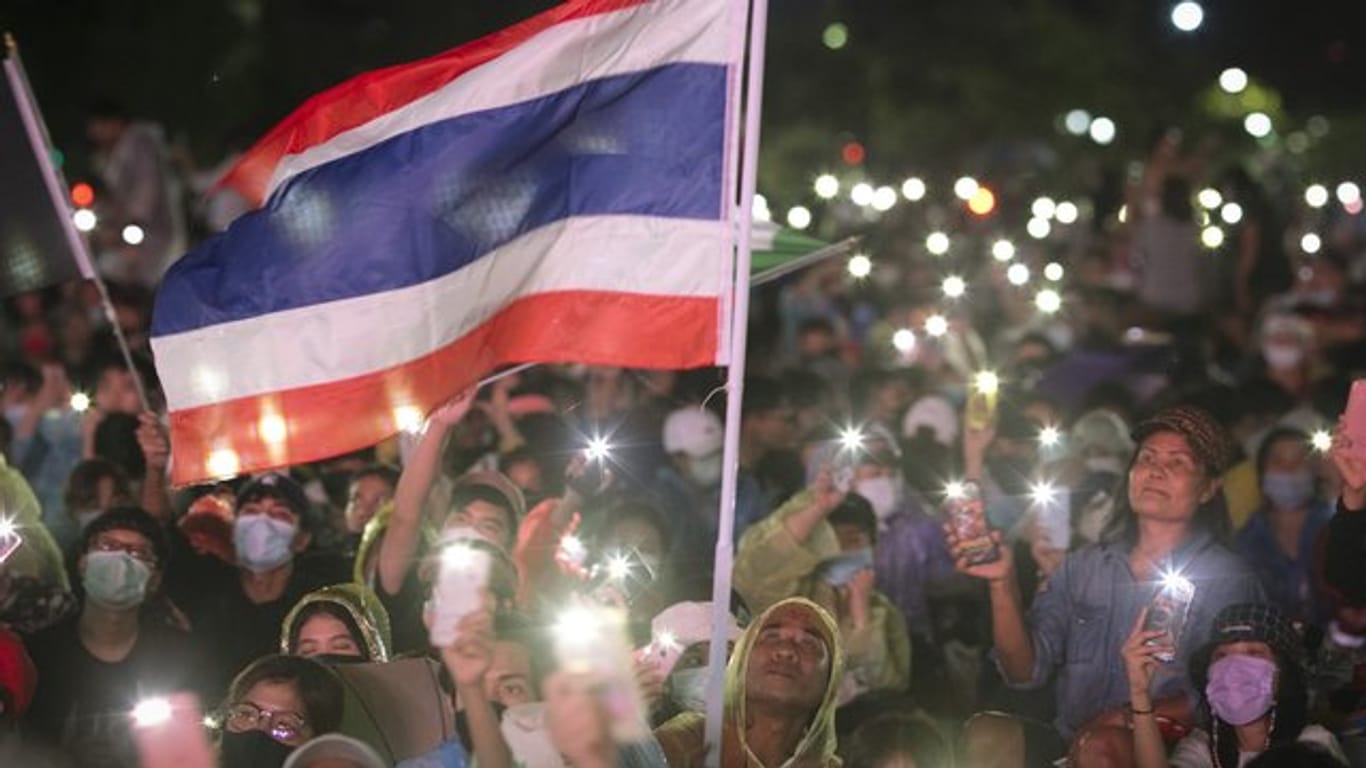 Pro-Demokratie-Aktivisten versammeln sich zu einem Protest in Bangkok und leuchten mit ihren Handys.