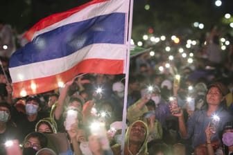 Pro-Demokratie-Aktivisten versammeln sich zu einem Protest in Bangkok und leuchten mit ihren Handys.