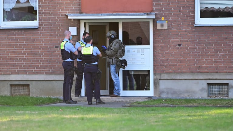 Krefeld: Polizei und ein SEK-Beamter stehen vor der Eingangstür eines Mehrfamilienhauses. In einer Wohnung im Haus hat sich möglicherweise ein Mann mit vier Kindern verschanzt.