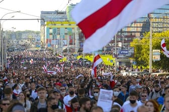 Demonstranten mit alten belarussischen Nationalflaggen gehen nach einer Kundgebung der Opposition durch Minsk, um gegen die offiziellen Ergebnisse der Präsidentschaftswahlen zu protestieren.