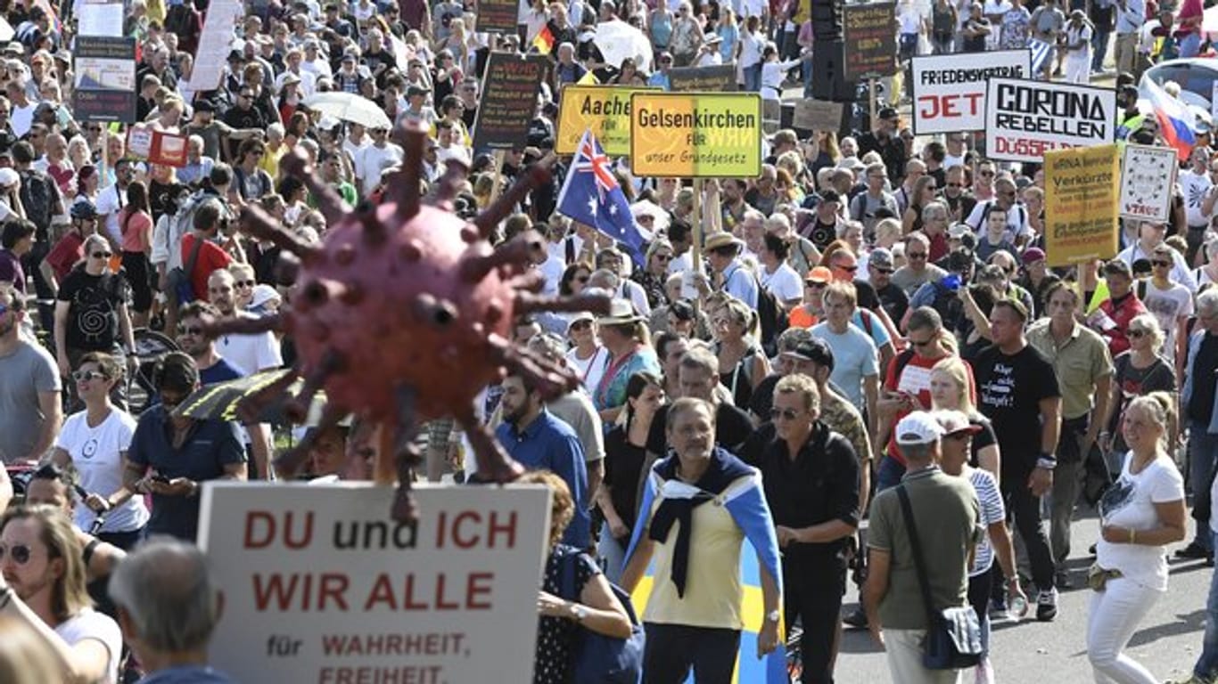 Teilnehmer einer Demonstration protestieren mit Schildern auf den Rheinwiesen gegen die Maßnahmen zur Bekämpfung des Coronavirus.