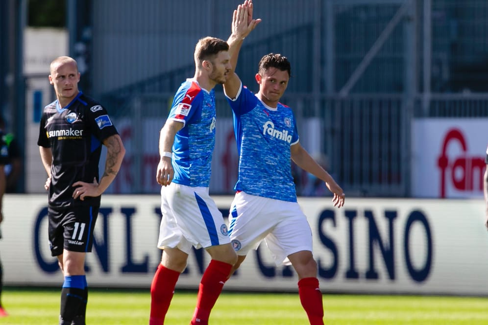 Kiels Mühling (M.) und Reese jubeln im Spiel gegen Paderborn.