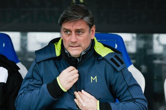 Der Karlsruher Sportdirektor Oliver Kreuzer sitzt während eines Spiels auf der Bank.