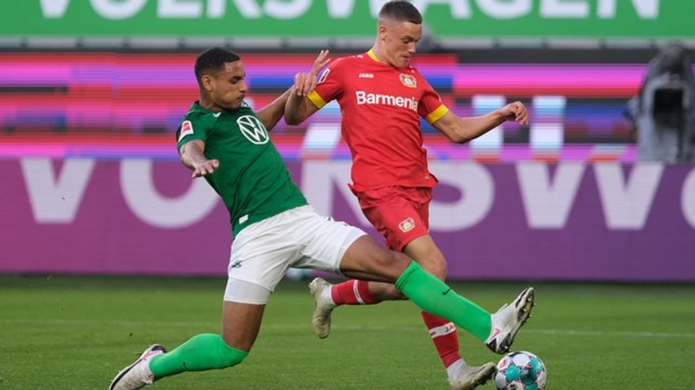 Wolfsburgs Neuzugang Maxence Lacroix (l) setzt gegen Leverkusens Talent Florian Wirtz zur Grätsche an.