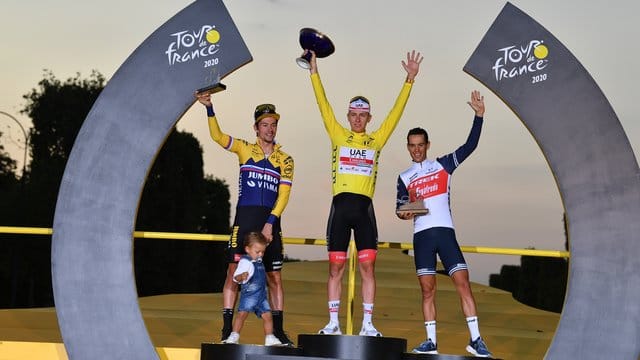 Der Zweitplatzierte Primoz Roglic (l-r) (mit seinem Sohn Lev), Tour-Sieger Tadej Pogacar und der Drittplatzierte Richie Porte feiern auf dem Podium.