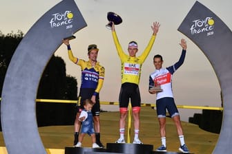 Der Zweitplatzierte Primoz Roglic (l-r) (mit seinem Sohn Lev), Tour-Sieger Tadej Pogacar und der Drittplatzierte Richie Porte feiern auf dem Podium.