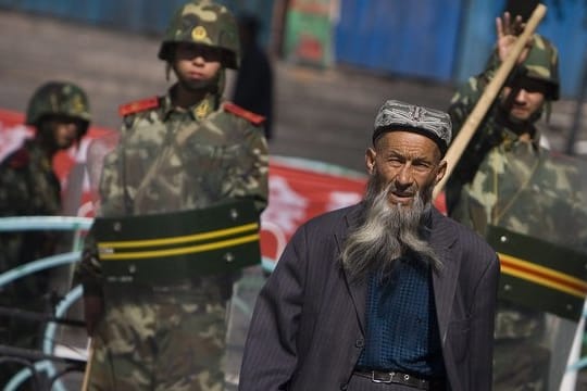 Ein Angehöriger der uigurischen Minderheit in der Unruheregion Xinjiang in Nordwestchina geht vorbei an chinesischen Sicherheitskräften.